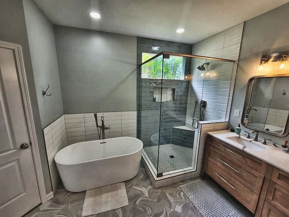 A bathroom with a bathtub , sink , shower and mirror.