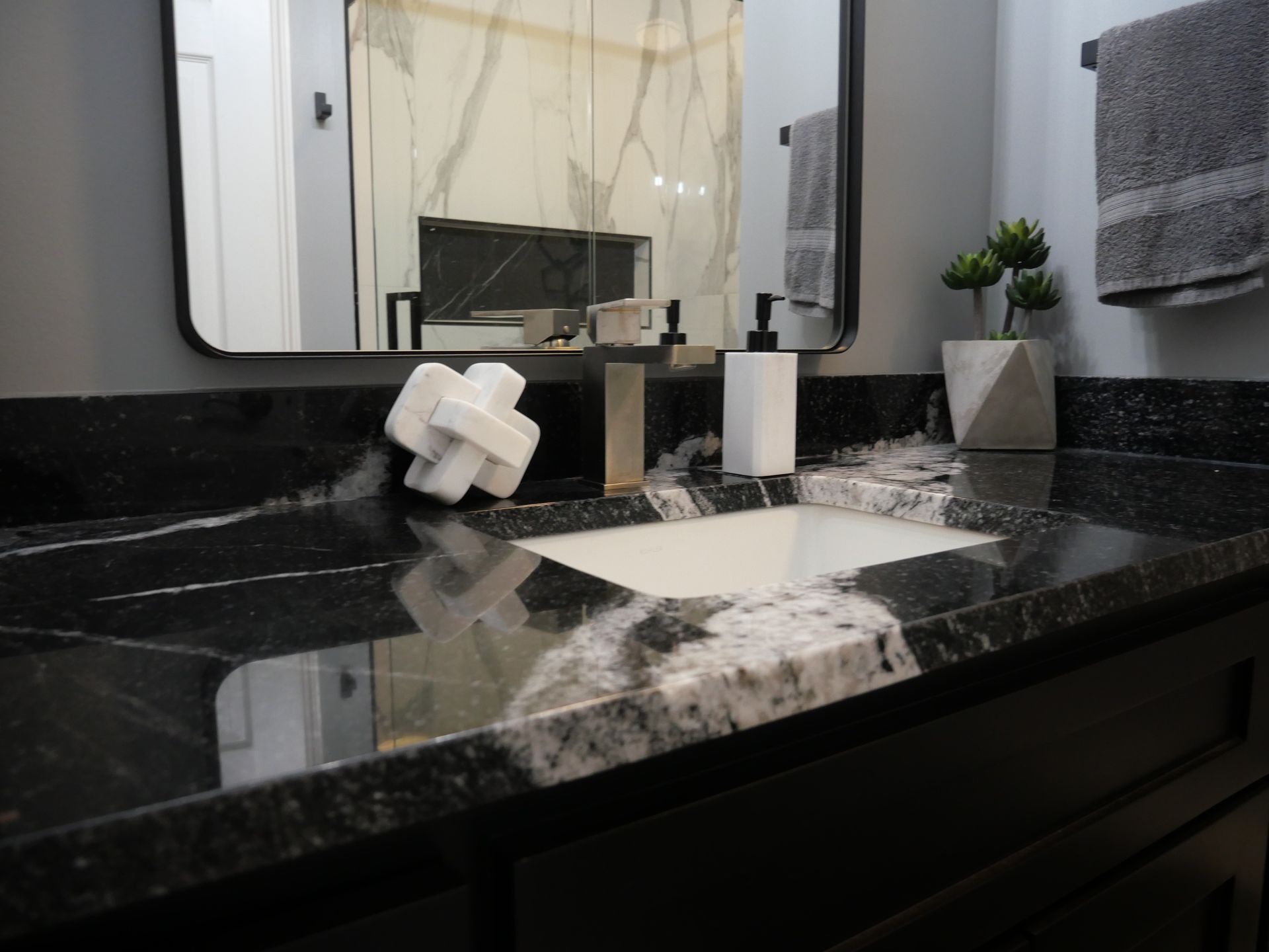 A bathroom with a black counter top and a white sink