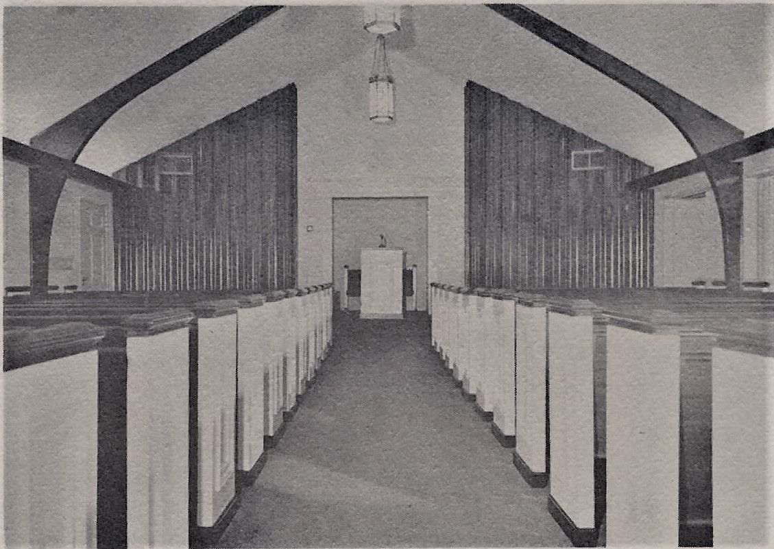 Symmetrical black-and-white view of a long hall with rows of cabinets and a central doorway at the end