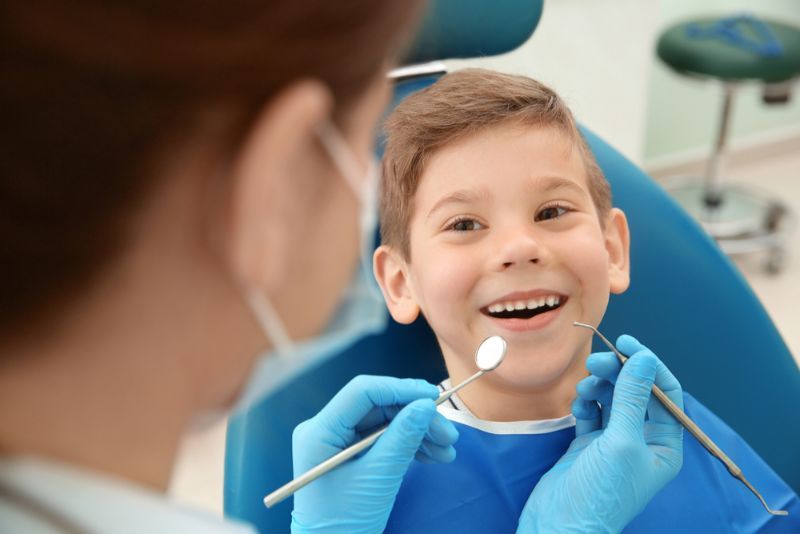 A Young Boy Is Sitting in A Dental Chair While a Dentist Examines His Teeth — Byron Bay Dental in Byron Bay, NSW