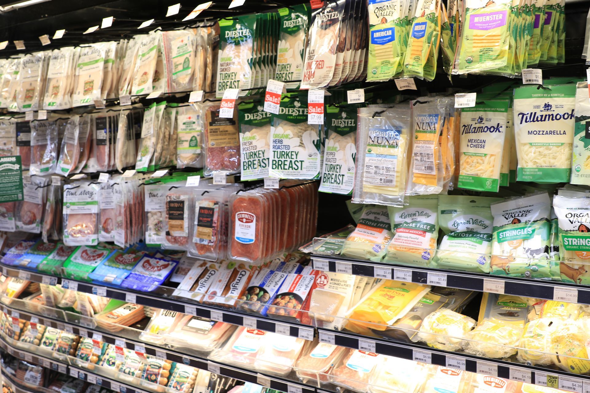 Grocery store shelf stocked with assorted packaged fresh vegetables and salads in clear plastic containers