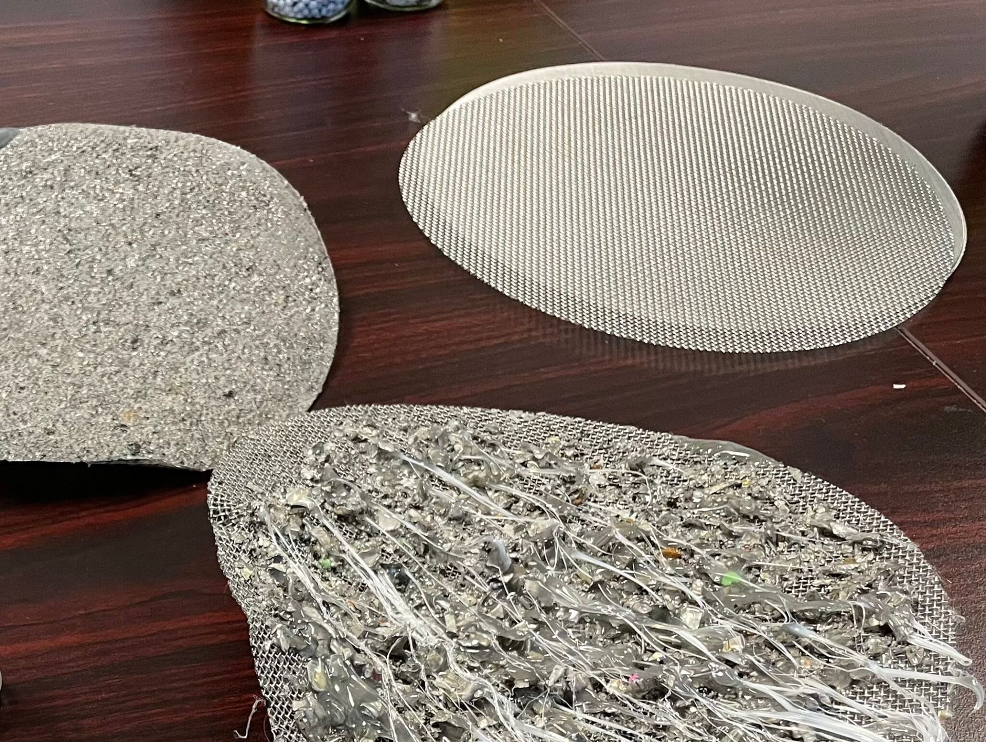 Three irregularly shaped, textured material samples on a dark wooden surface.