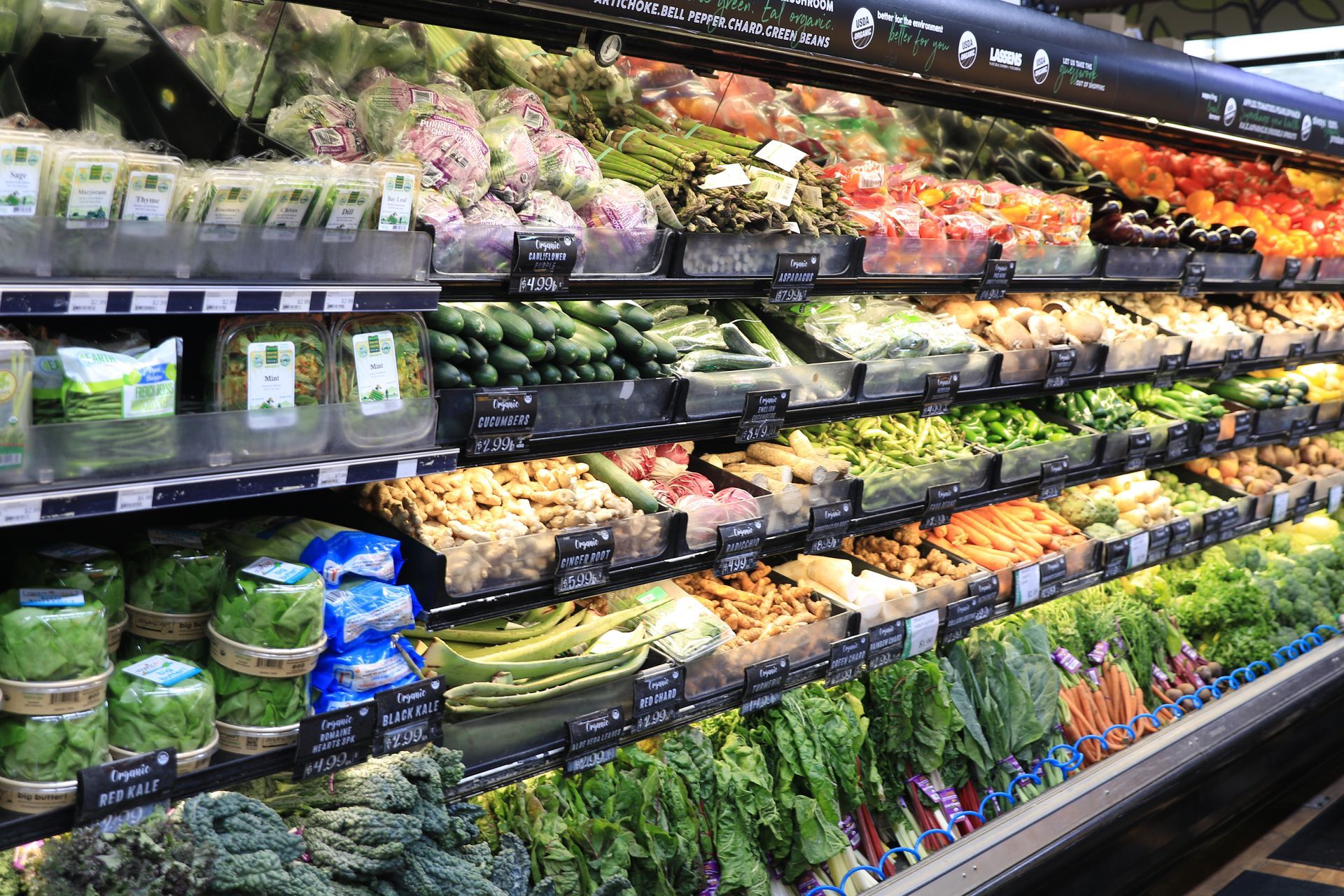 An organized organic produce section in a grocery store with shelves full of fresh fruits and vegetables.