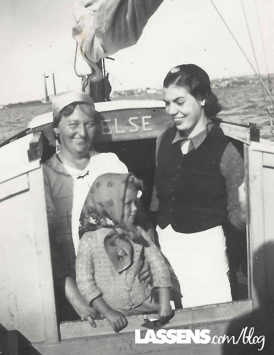 Three people stand on a boat named