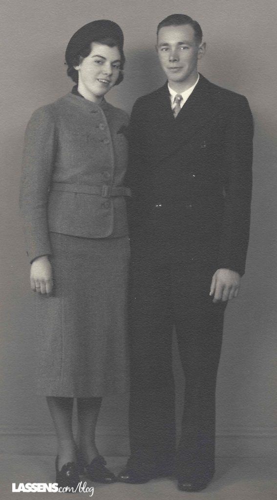 Formal portrait of a man and a woman standing close. The woman wears a skirt suit, the man a dark suit.
