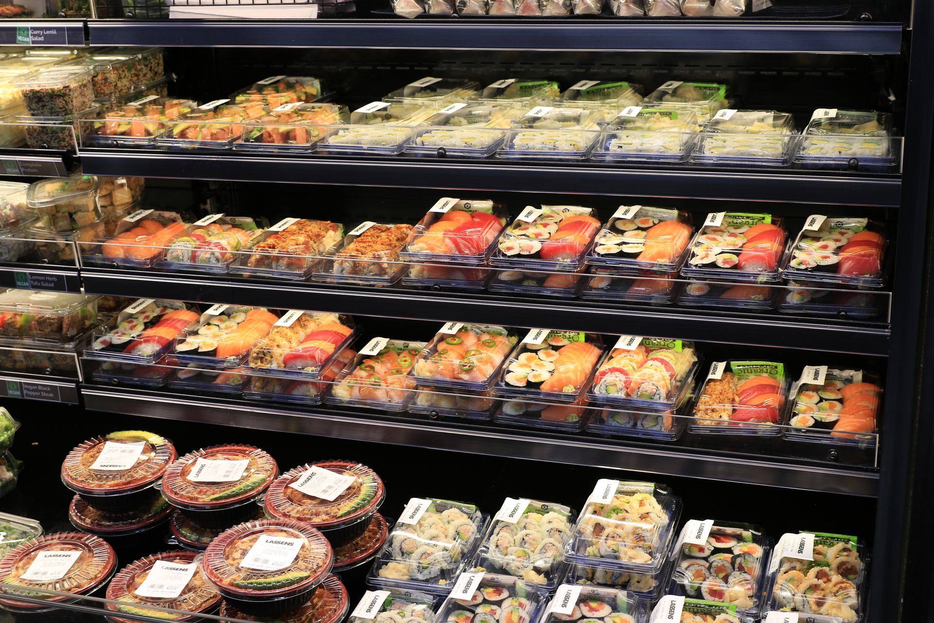 Supermarket deli shelves stocked with neatly arranged packaged prepared meals and salads