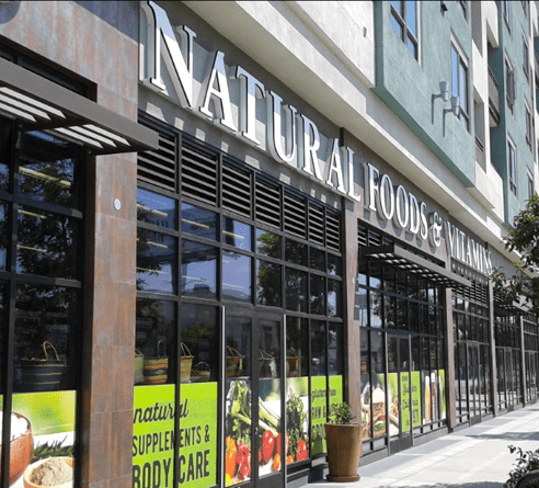 A storefront for a natural foods and market store with glass windows, metal awnings, and signage for supplements.