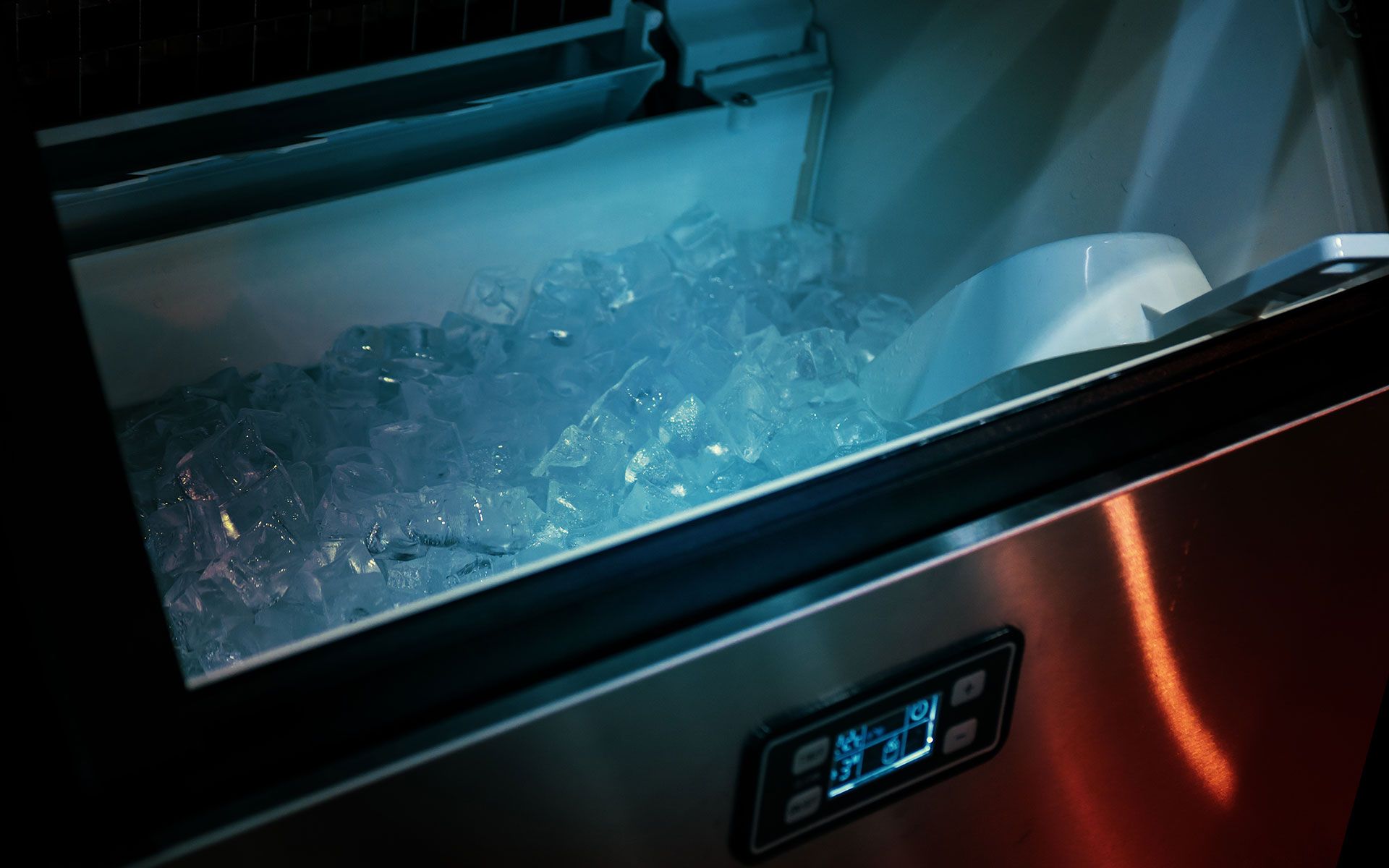 A stainless steel ice maker is filled with ice.