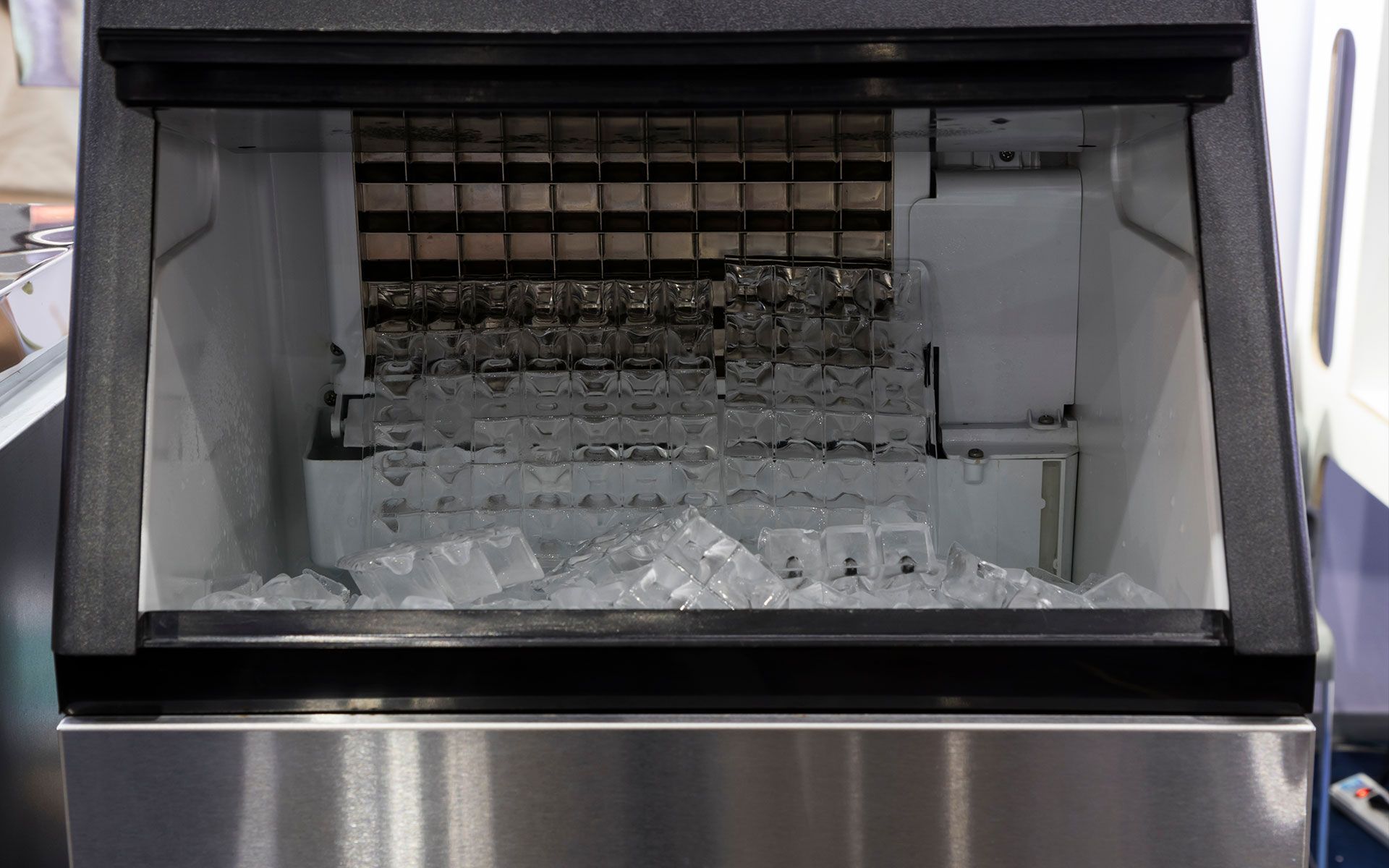 A stainless steel ice machine is filled with ice cubes.