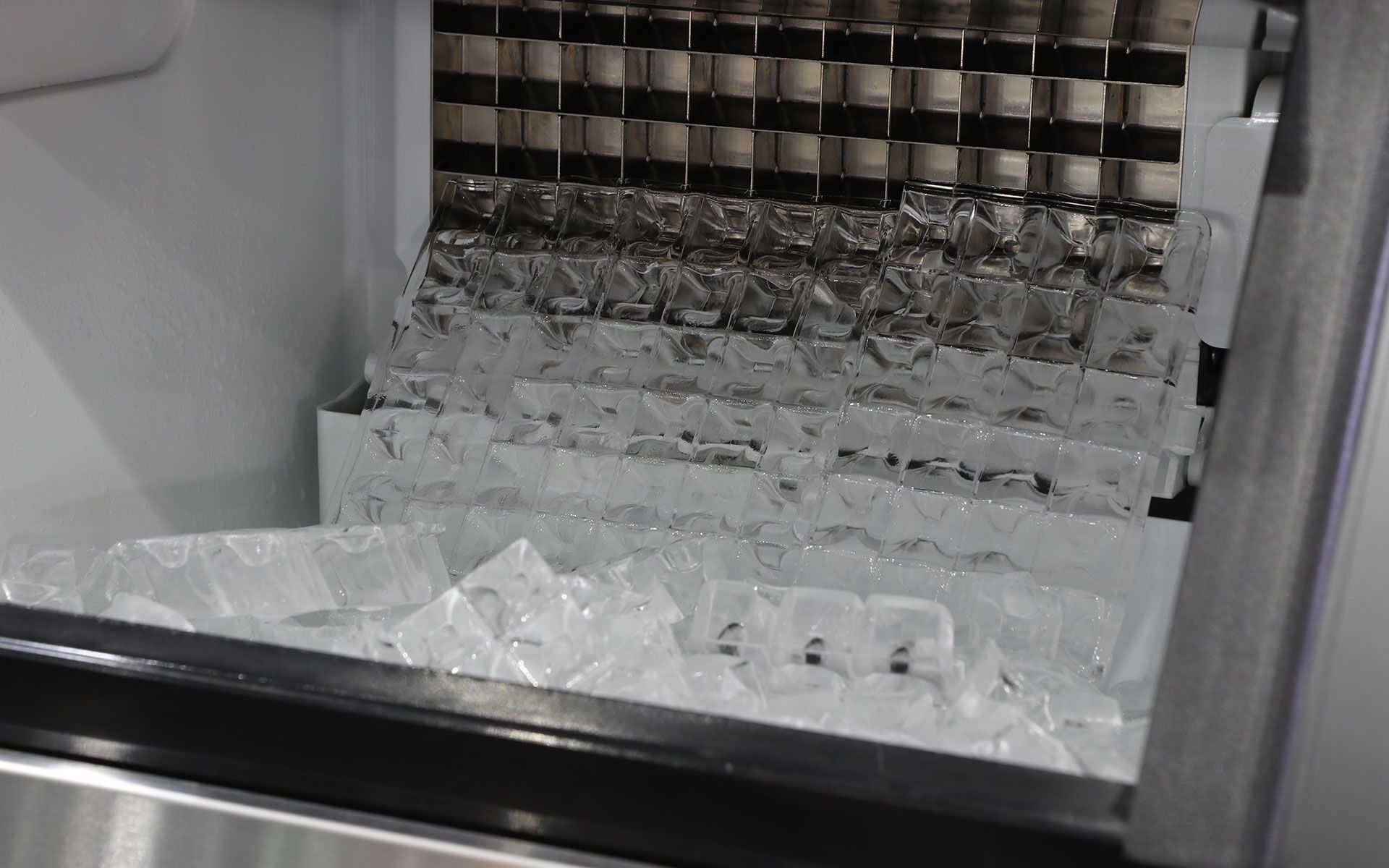 A machine is making ice cubes in a refrigerator.