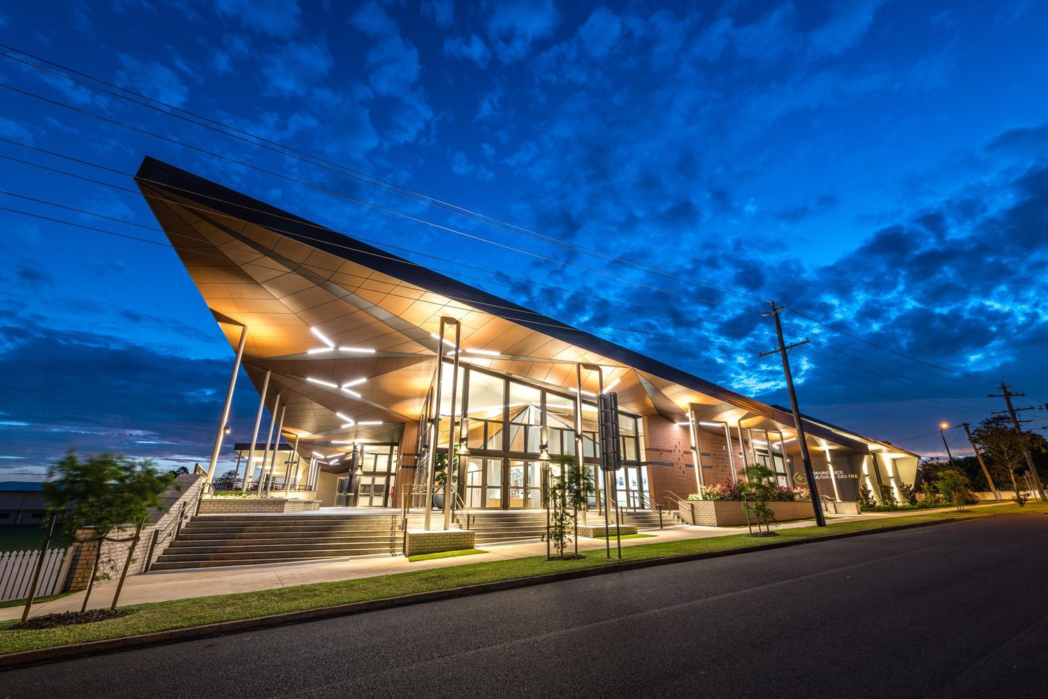 A large building is lit up at night with a blue sky in the background.