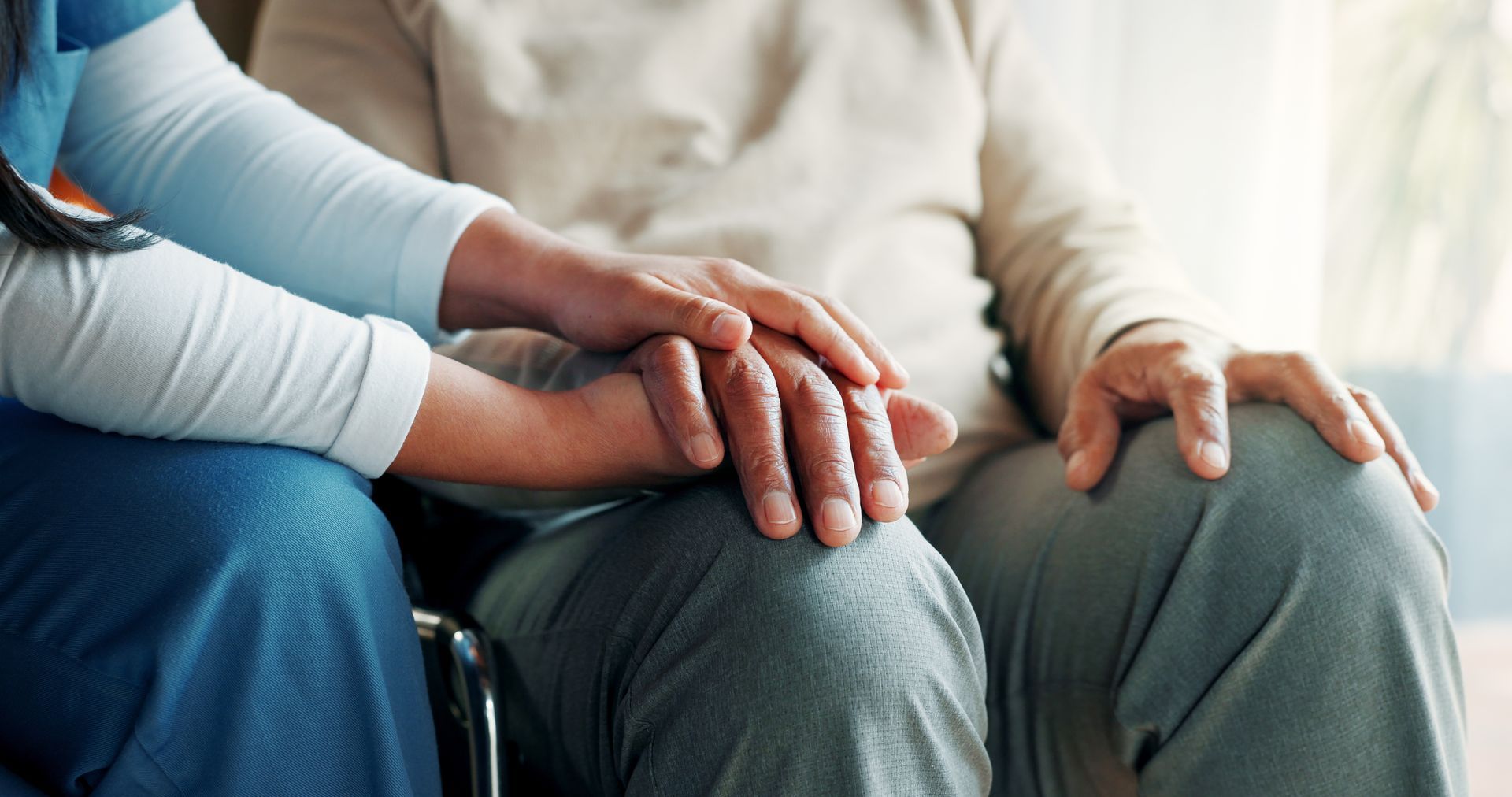 Two people holding hands on a couch, one comforting the other
