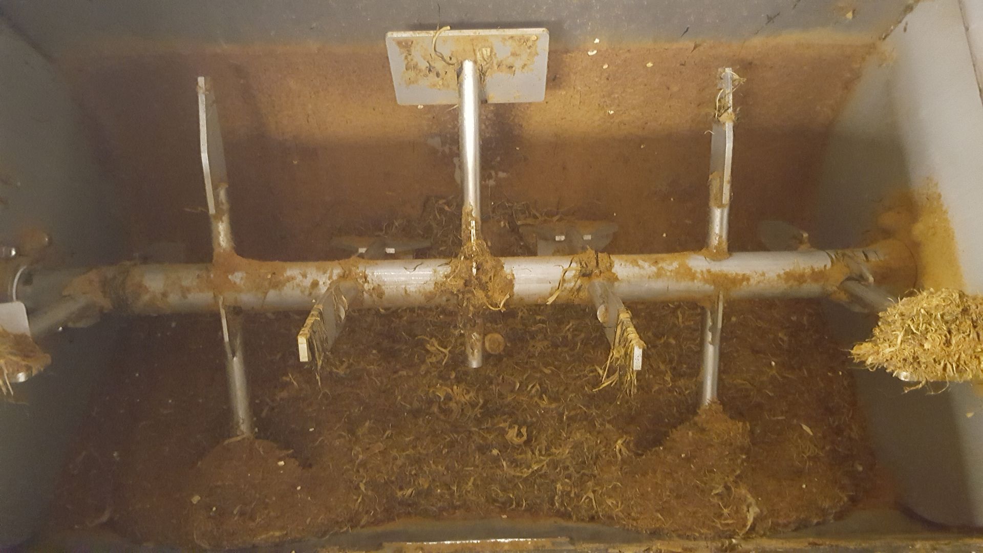 À l'intérieur d'un mélangeur d'aliments, les lames sont recouvertes d'un mélange d'aliments bruns et jaunes.
