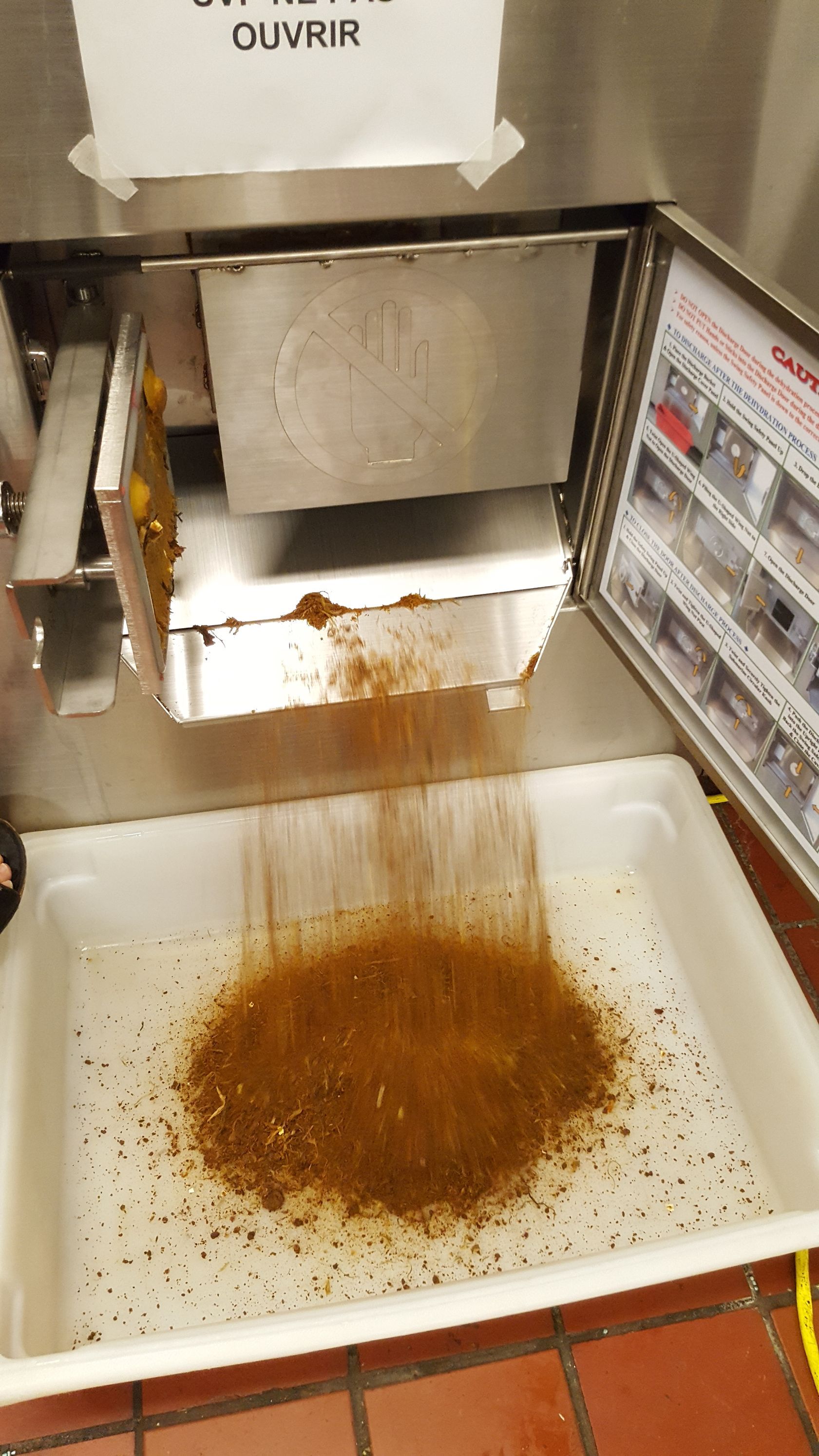 Machine distribuant des épices brunes dans un plateau blanc.