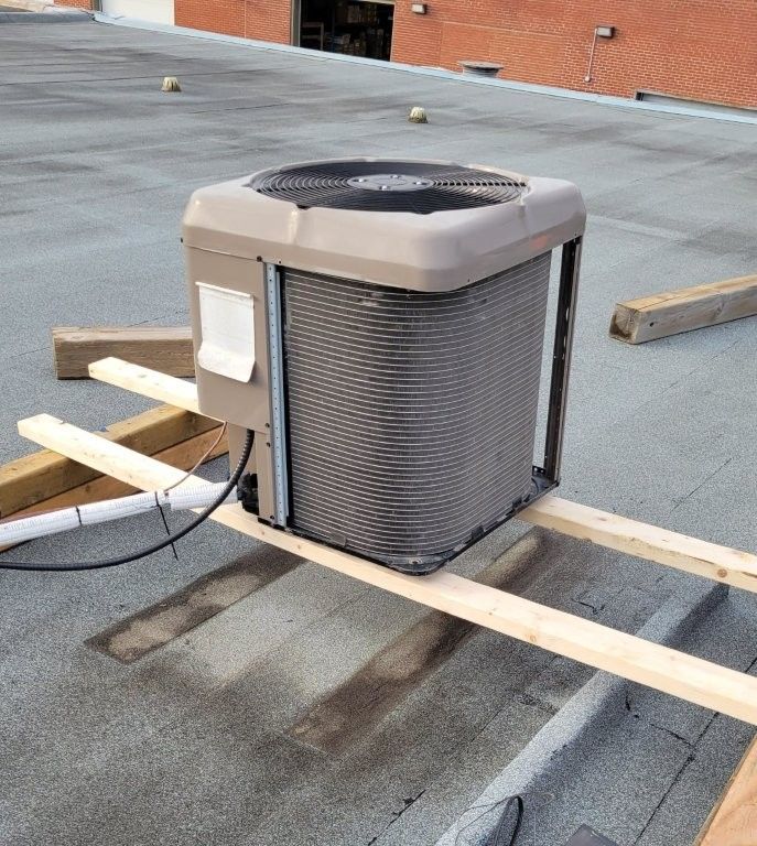 Unité de climatisation sur un toit plat, soutenue par des poutres en bois.