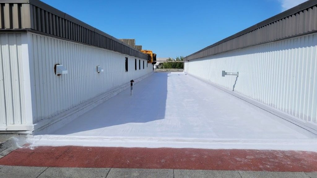 Vue d'un toit plat à la peinture blanche entre deux bâtiments aux façades blanches par une journée ensoleillée.