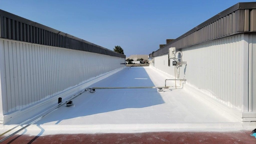 Long toit blanc orné de bordures noires et ciel d'un bleu limpide.