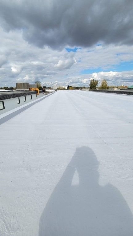 L'ombre d'une personne sur un toit plat blanc sous un ciel nuageux.
