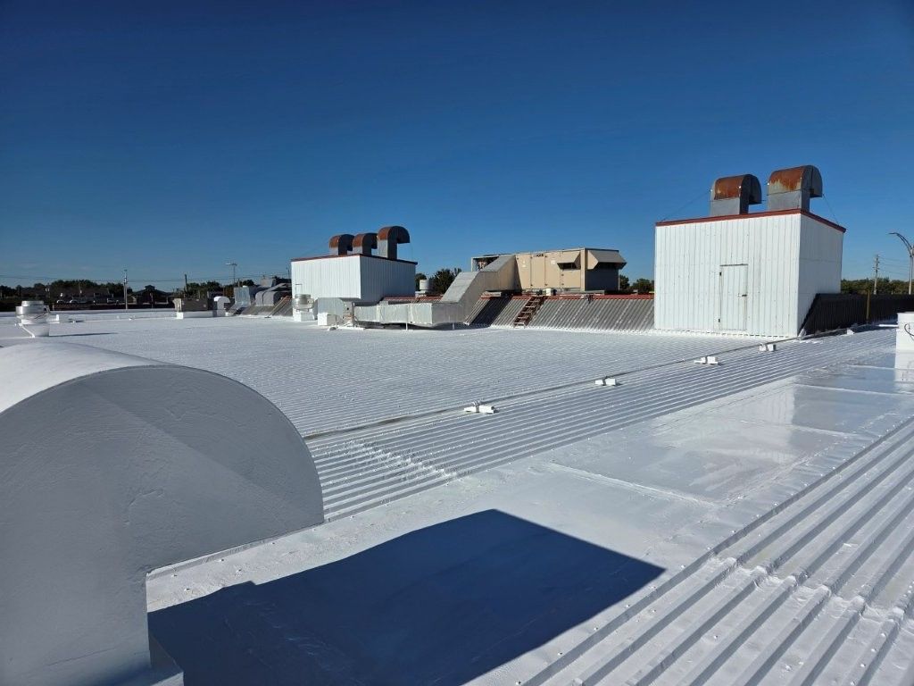 Toit blanc avec des structures industrielles se détachant sur un ciel bleu limpide.