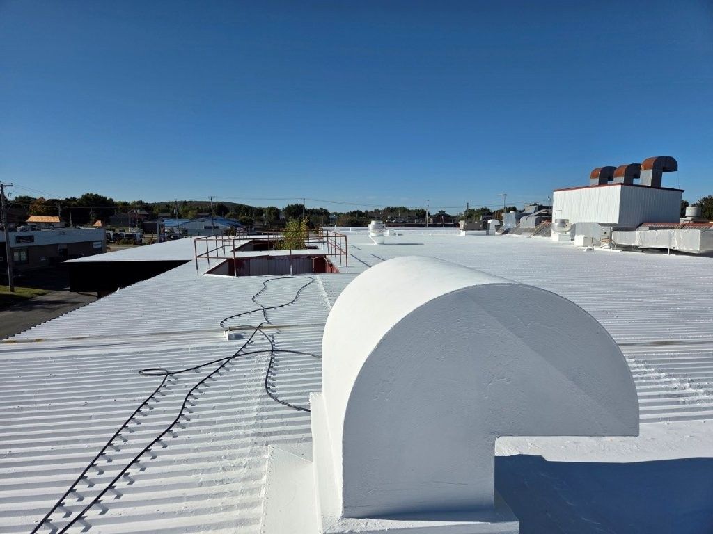 Toit blanc orné d'éléments architecturaux, guirlandes lumineuses et ciel bleu azur.