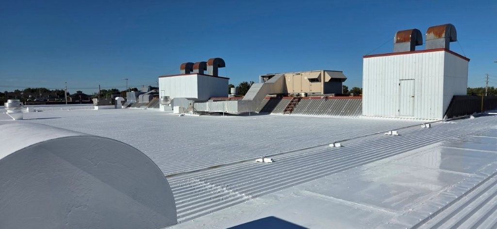Toiture commerciale blanche avec plusieurs unités mécaniques sous un ciel bleu dégagé.