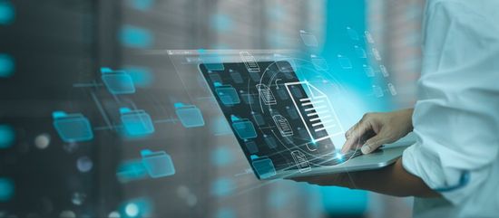 Persona che utilizza un computer portatile con file digitali e visualizzazione di dati, toni blu.