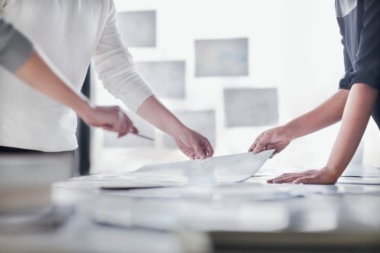 Persone che collaborano attorno a un tavolo, esaminando documenti e pianificando.