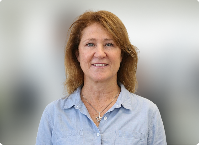 Smiling woman in a light blue shirt against a softly blurred background