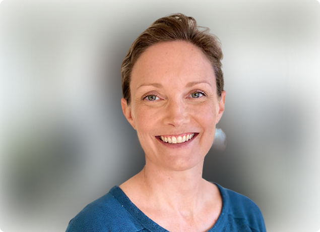Smiling woman in a blue top against a blurred light background