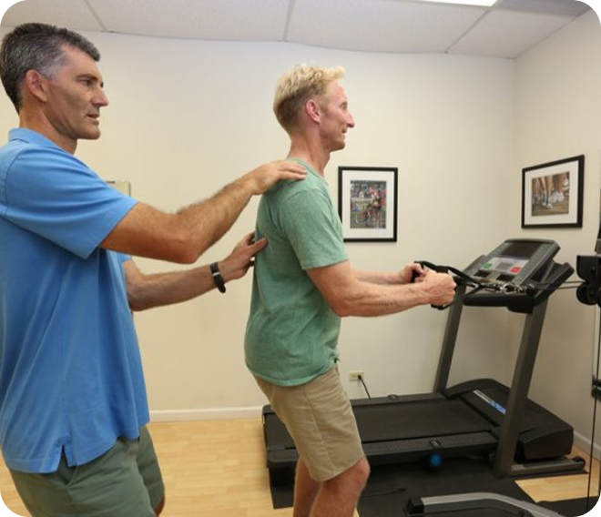 Trainer guiding a man on a treadmill in a gym room
