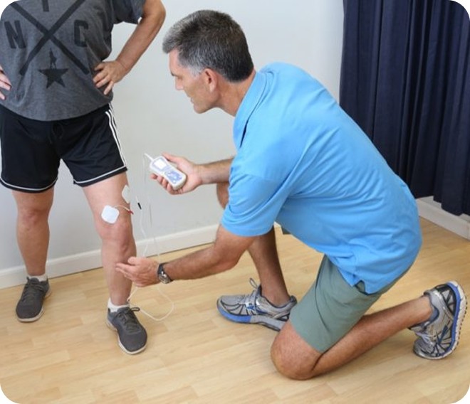 Physical therapist applying ointment to a patient's knee in a clinic room