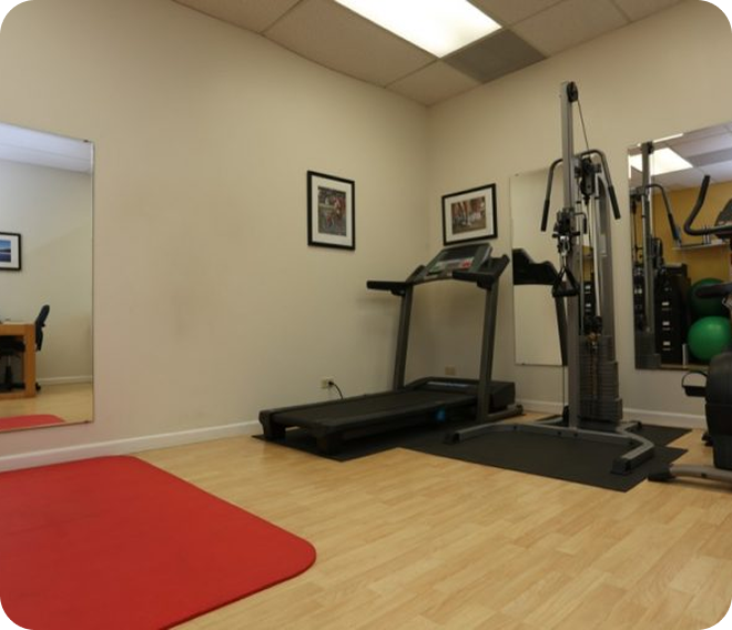 Small gym room with treadmill, exercise machine, red mat, and wall mirrors.