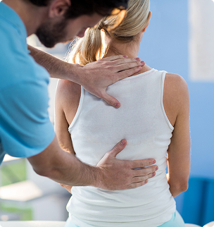 Physical therapist massaging a seated patient's neck and back in a bright clinic