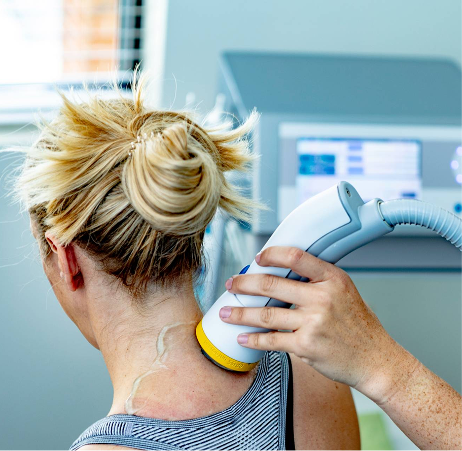 Person using a handheld device on upper back in a clinical setting