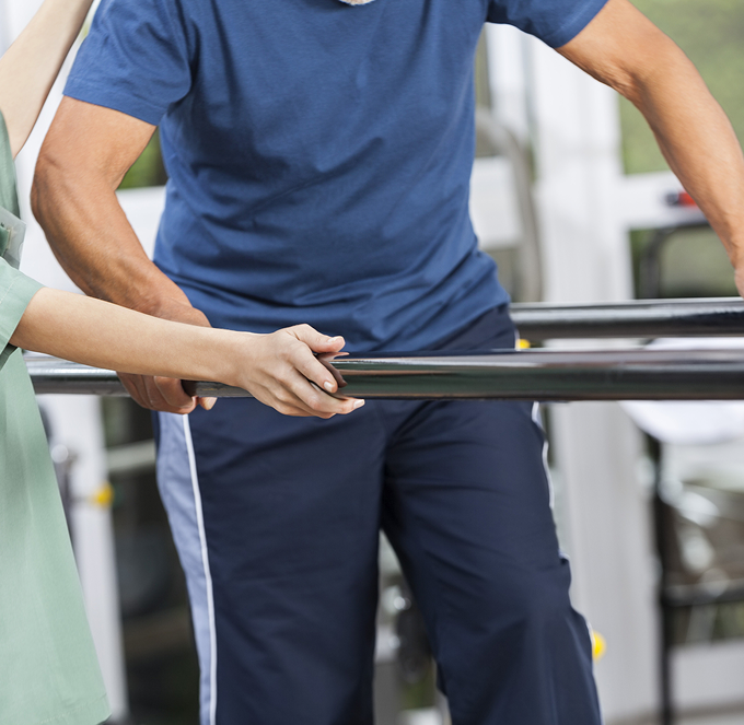 Two people holding a black metal bar in a gym or workshop setting