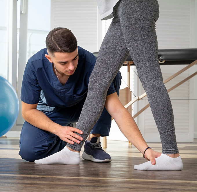 Physical therapist examining a patient’s ankle in a bright studio gym