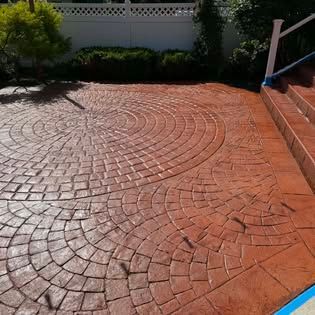 Brick-pattern stamped concrete patio with circular design in sunlight