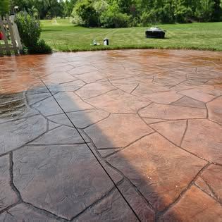 Stamped concrete patio overlooking a green lawn with trees in the background.