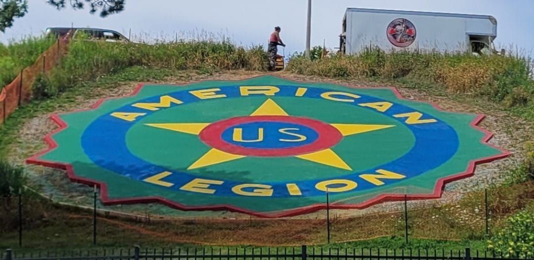 Colorful Manila, Palawan welcome mural on a grassy hill, with a person and truck in the background