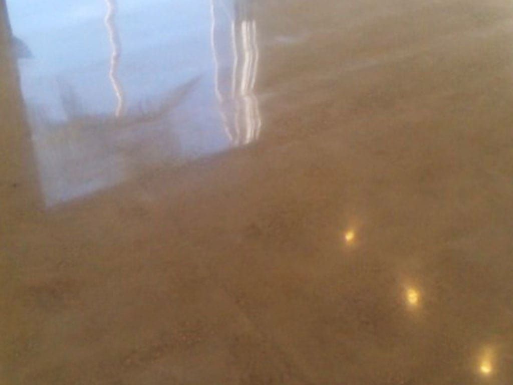 Shiny tan polished concrete floor with reflections of a window.