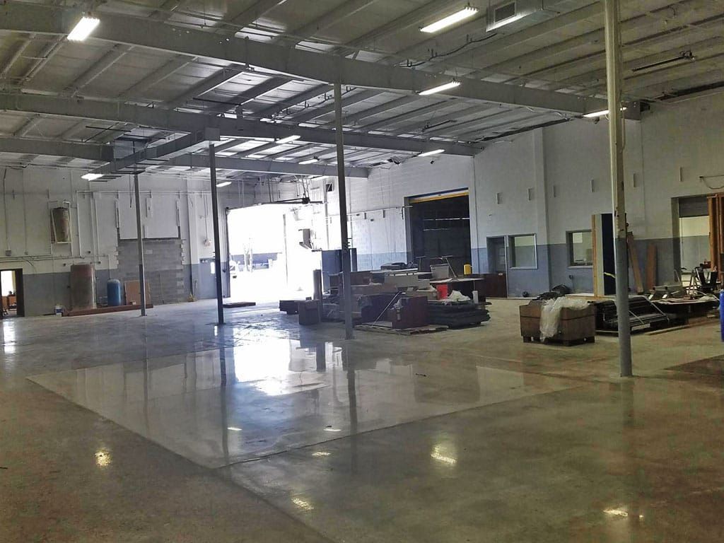 Empty warehouse interior with open bay doors, and polished concrete floor.