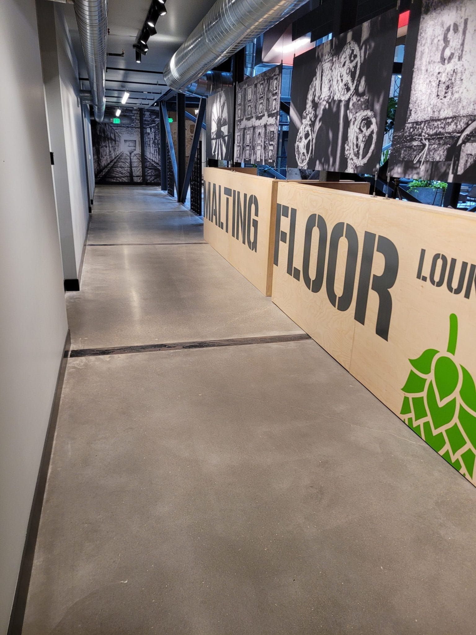 Long indoor hallway with concrete floor and graffiti-style wall art on the right