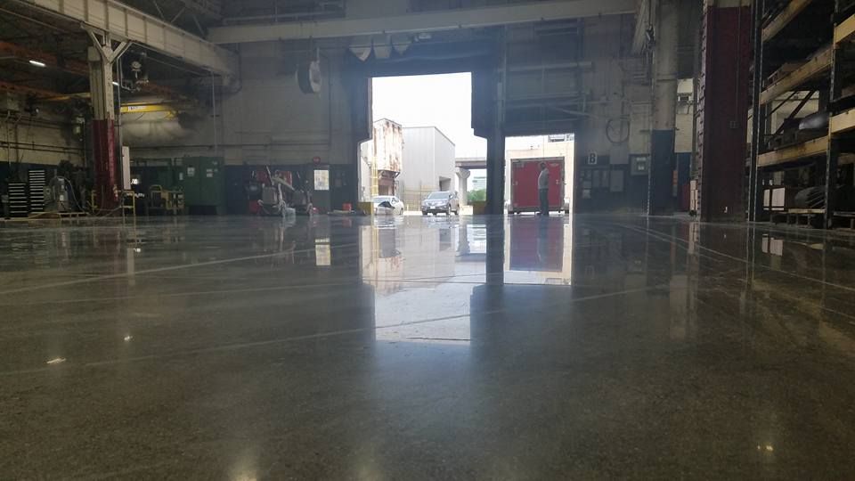 Empty industrial warehouse with polished concrete and bright open doorway in the center