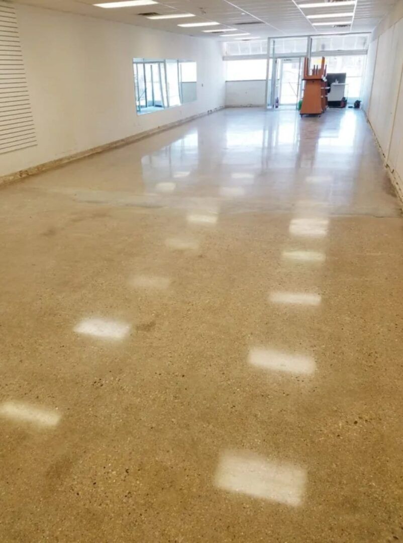 Commercial polished concrete hallway with white walls, windows, and sunlight reflecting on the floor