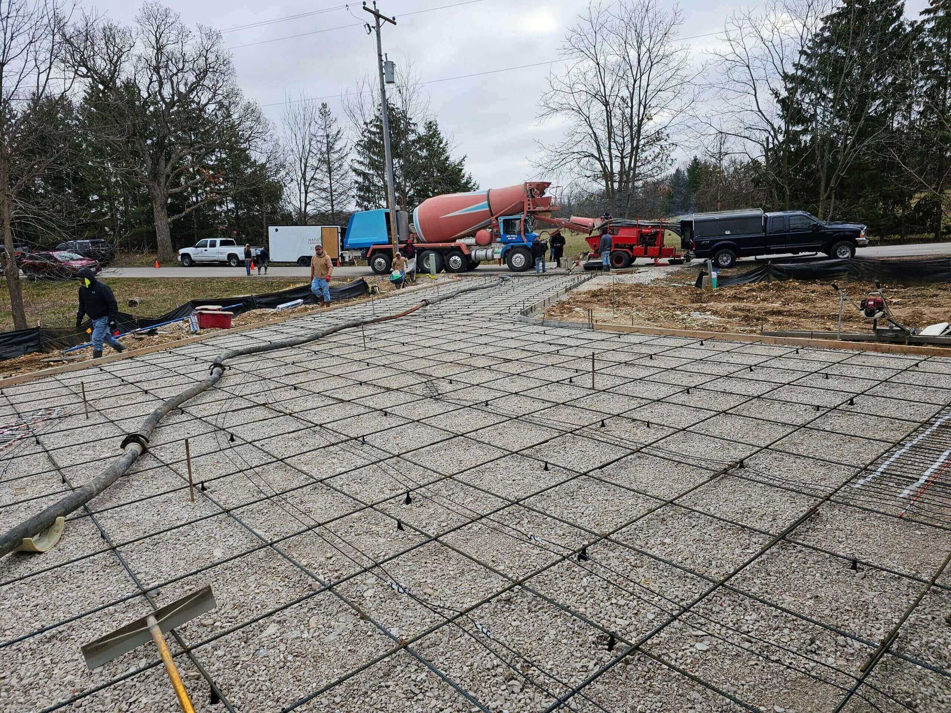 Concrete slab foundation rebar grid at a construction site with cement truck and workers in background