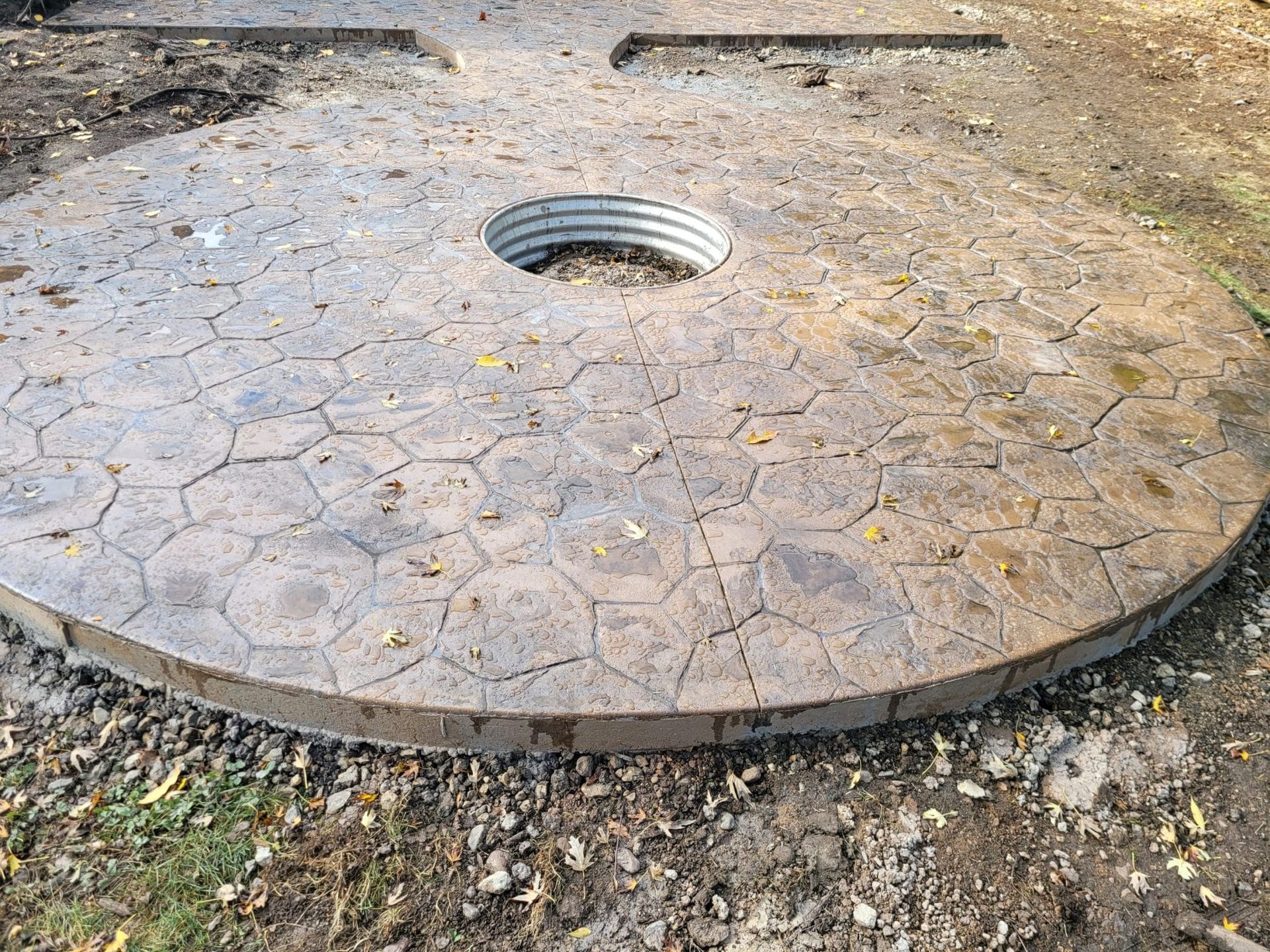 Custom circular stamped concrete patio extension with a central metal opening.