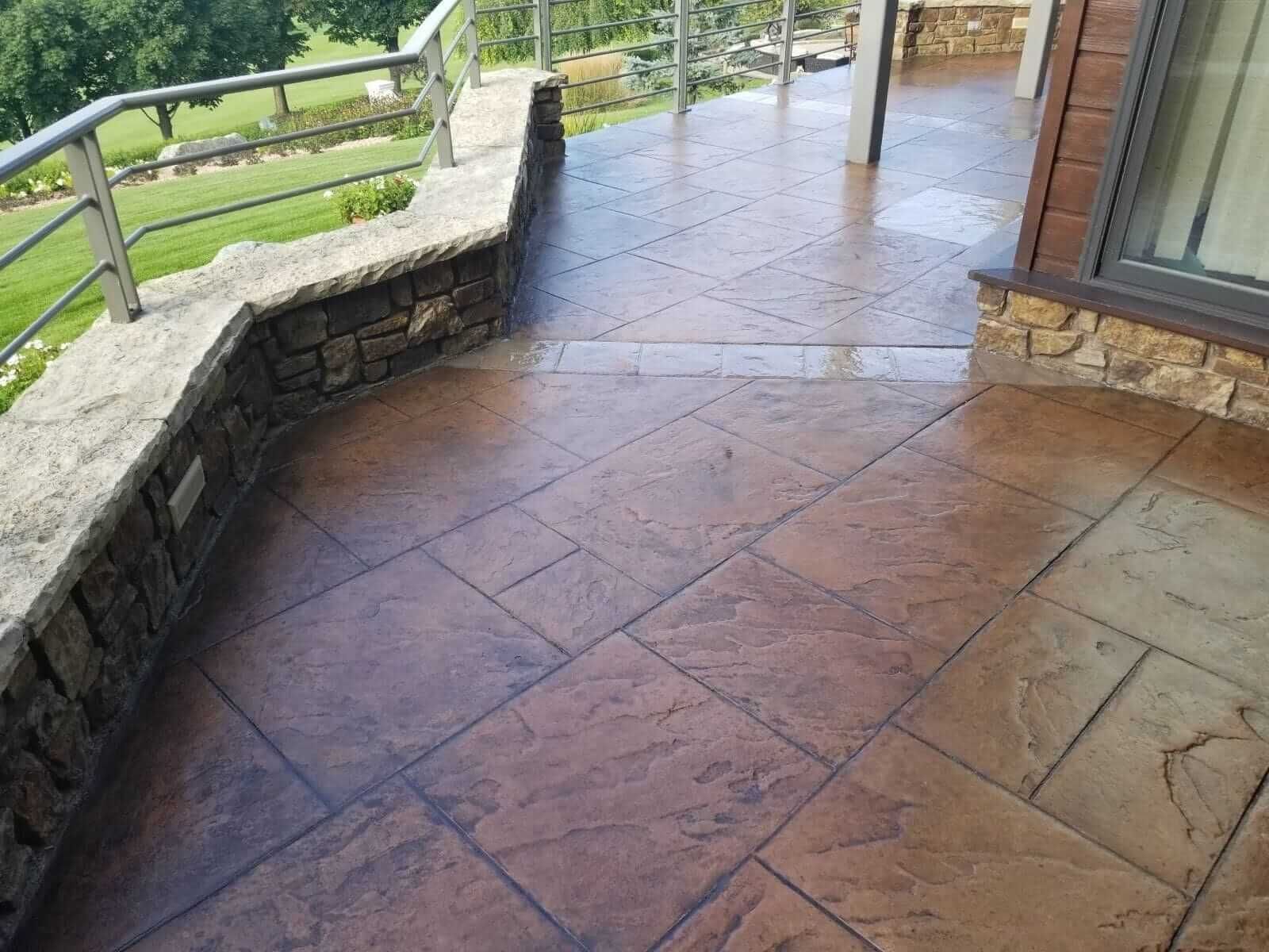 Stamped concrete patio with curved railing overlooking a green landscape
