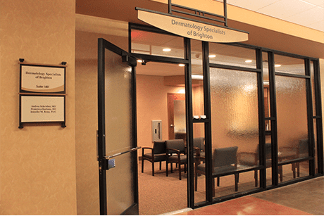 The entrance to Dermatology Specialists of Brighton, featuring a glass door and signage on a beige wall.