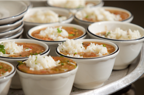 A tray of bowls of soup with rice on top