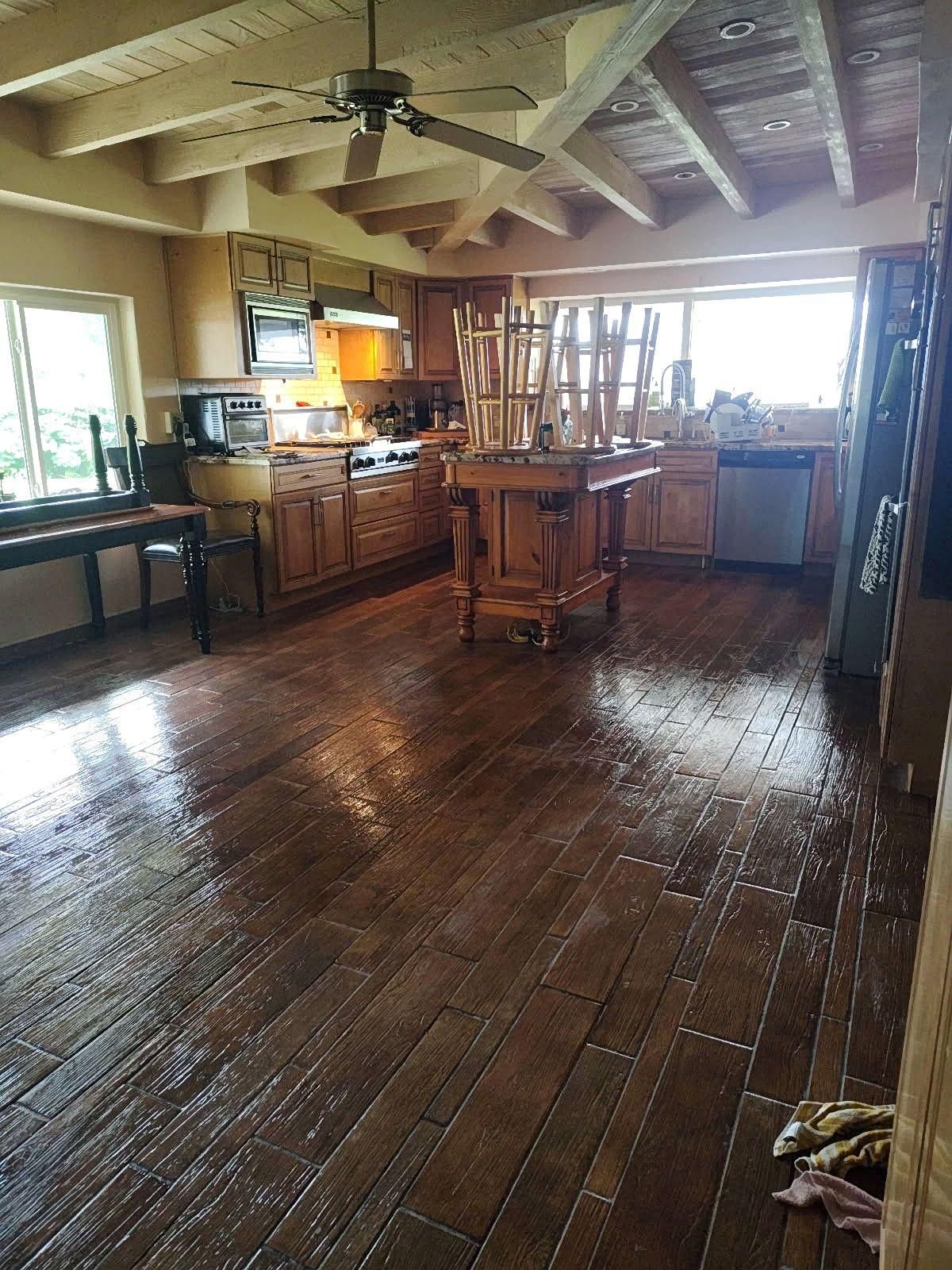 Rustic kitchen with dark wood floors, wood beams, cabinets, and a large island in natural light